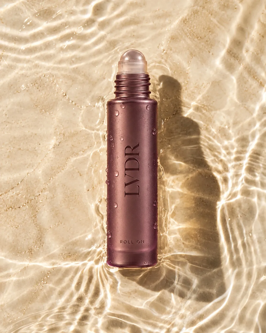 The Lavender Haze roll-on resting in sunlit water