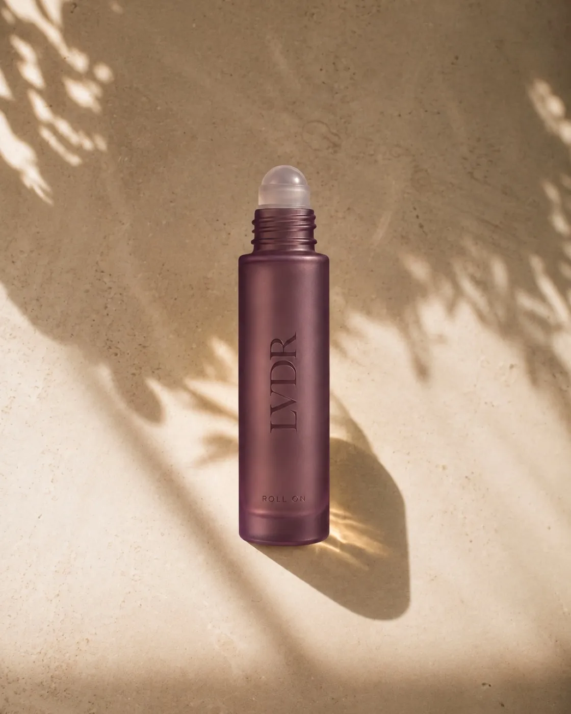LVDR Lavender Haze roll-on in frosted violet glass with a travertine cap